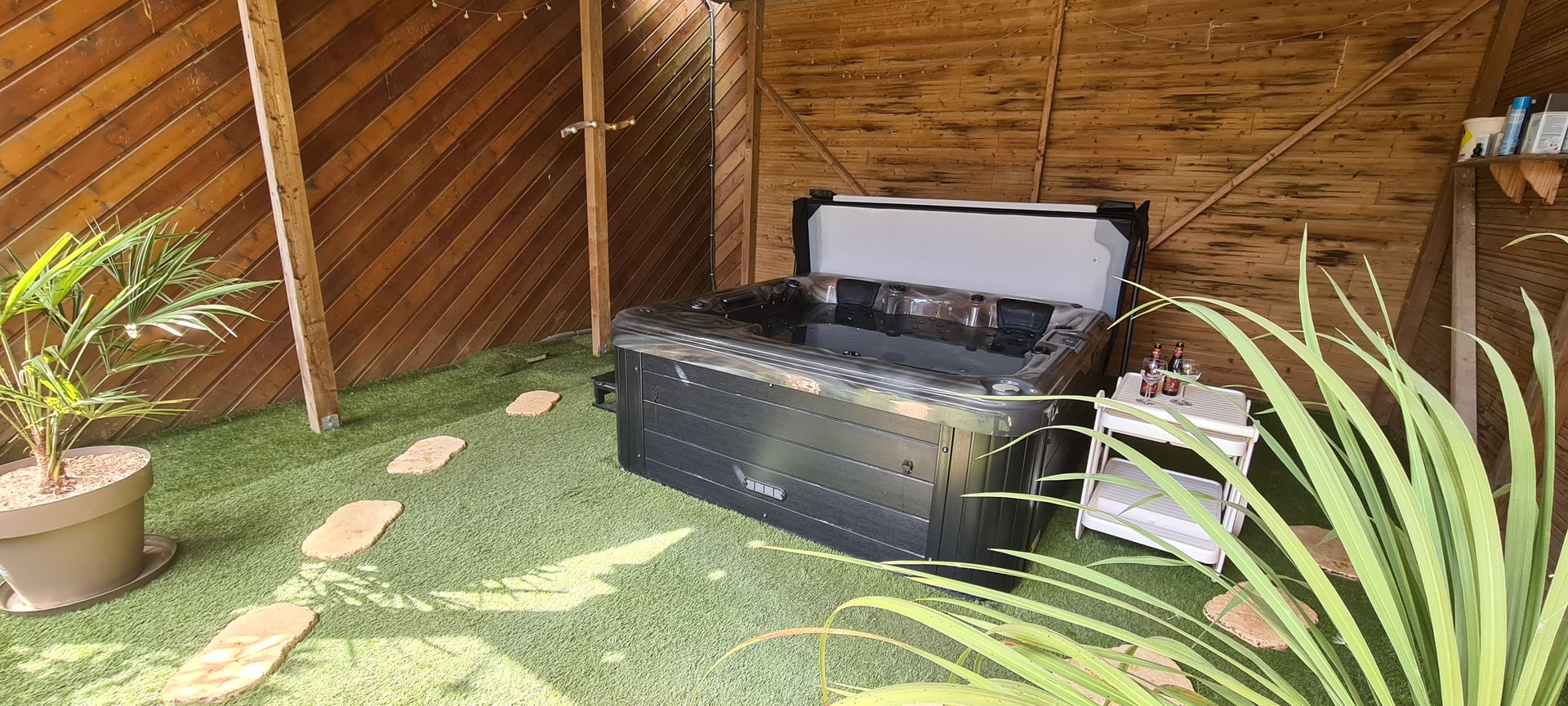 Jacuzzi installé dans un espace couvert en bois.